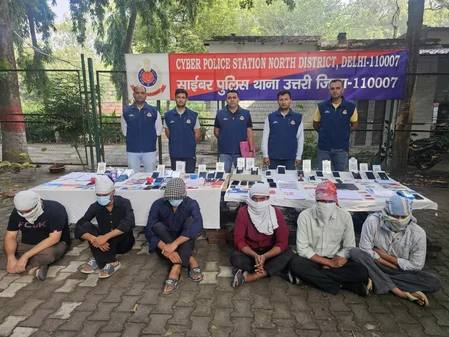 Delhi Police officers with the arrested accused and seized mobile phones and documents at the Cyber Police Station, North District, Delhi