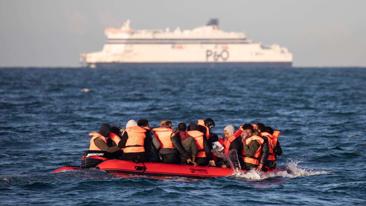 File photo of a crowded inflatable boat carrying people in life jackets across the English Channel, with a lifeboat vessel nearby