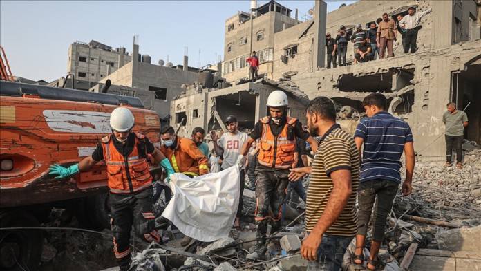 Palestinian civil defence workers carrying recovered remains through the rubble of destroyed buildings in Gaza (file photo)