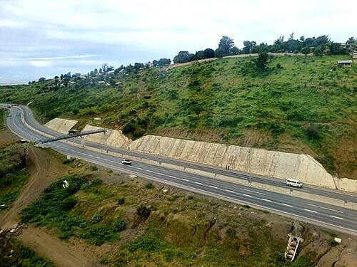 File photo of the Nairobi-Mombasa Highway in Kenya, a divided highway running through green hills with a bus and cars travelling on it