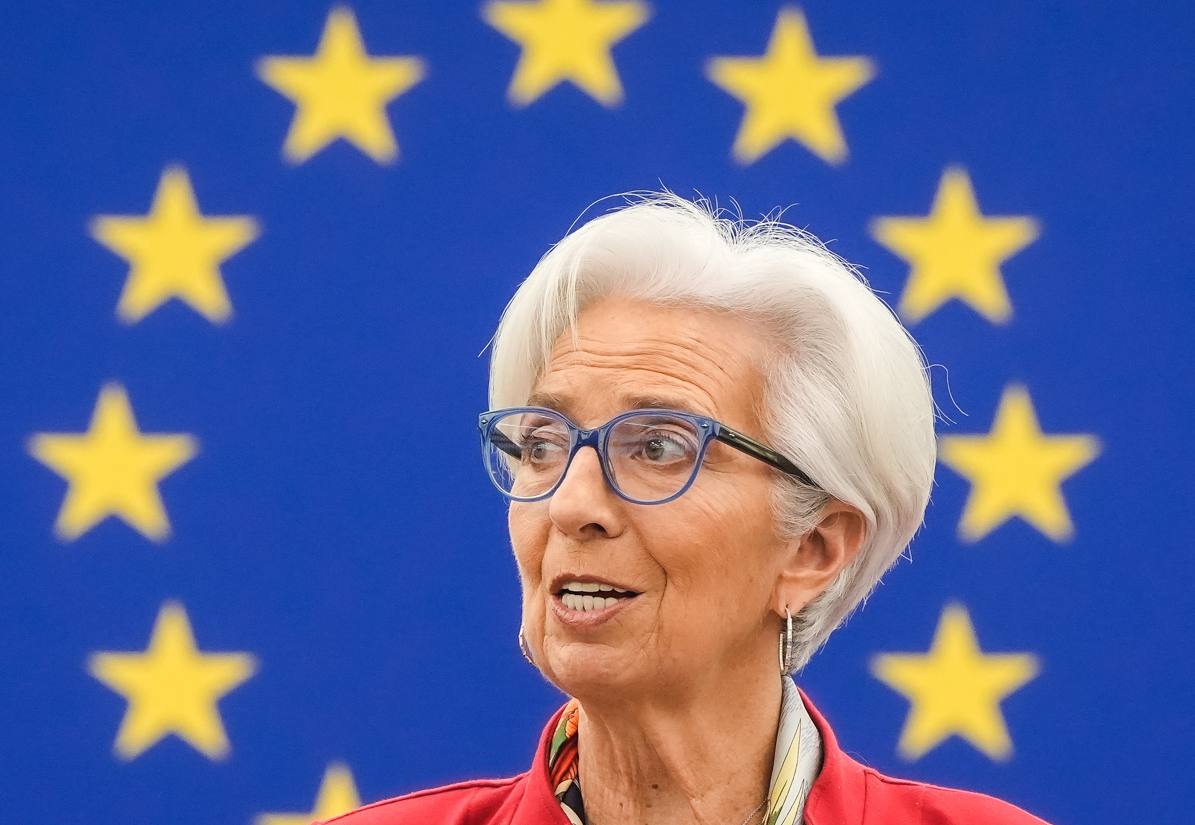 Christine Lagarde speaking at a European Parliament plenary session, with the circle of yellow stars of the European Union flag behind her