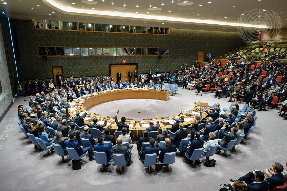 The UN Security Council chamber in New York during a vote, delegates seated around the horseshoe table