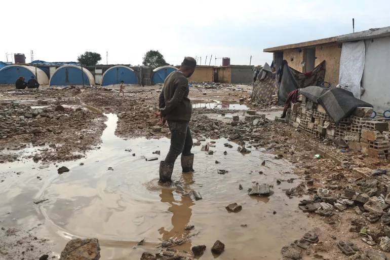 A displaced man stands in floodwater at the al-Talae displacement camp in Hasakah, northeastern Syria, after heavy rain on October 29, 2026
