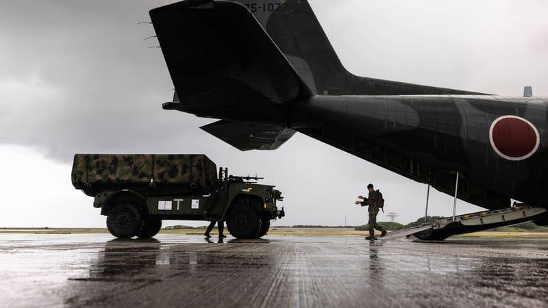 A covered U.S. NMESIS missile vehicle beside a Japan Air Self-Defence Force C-130 transport at Naha, Okinawa, during Keen Sword 27