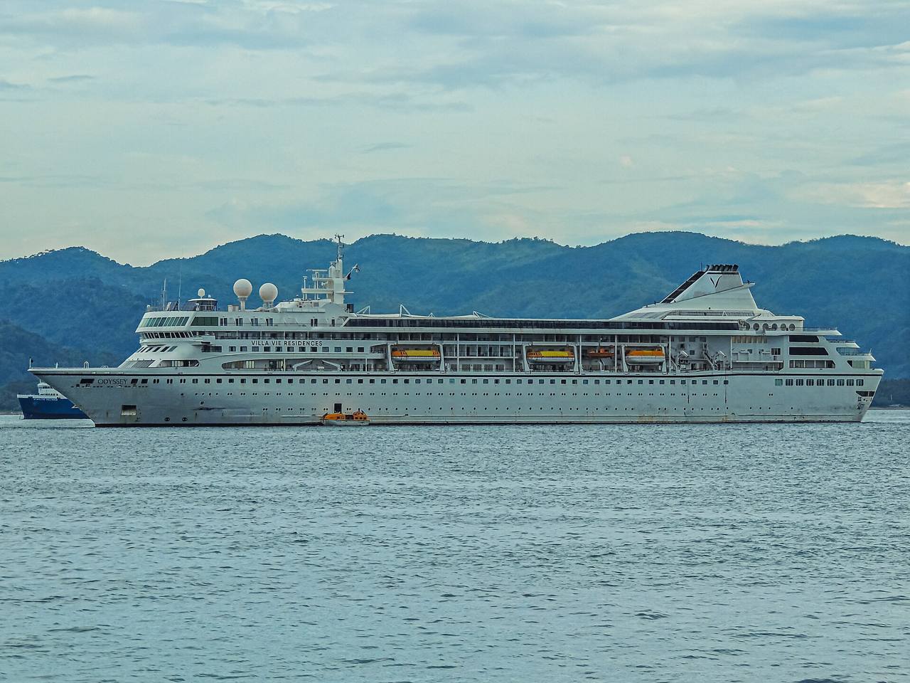 The residential cruise ship Villa Vie Odyssey at anchor in front of green hills (file photo, September 2025)