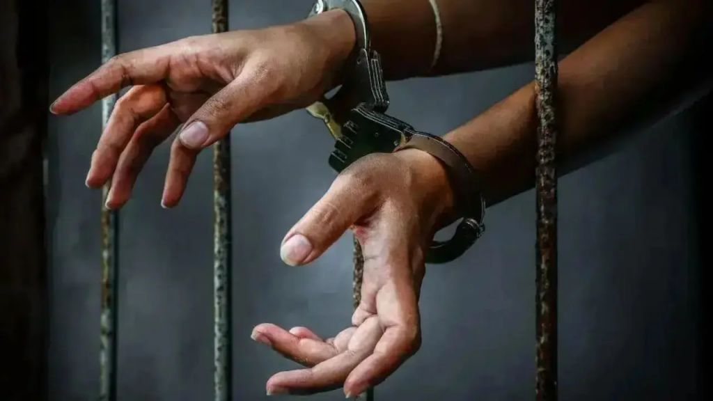 File photo: handcuffed hands behind prison bars