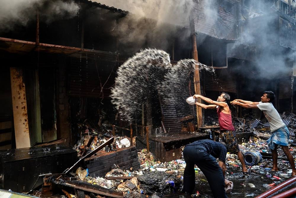 People dousing a smouldering market stall with water after a fire at a Kolkata market (file photo)