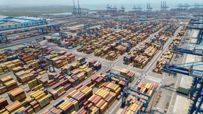 Aerial view of a container port in India, with rows of shipping containers and blue gantry cranes