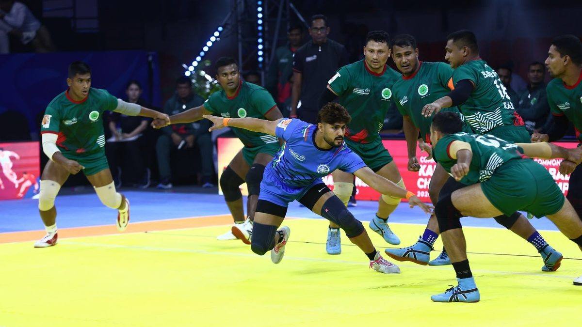 India raider in blue evading Bangladesh defenders in green during the Commonwealth Kabaddi Championship semifinal in Ahmedabad