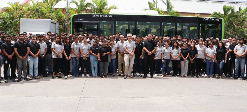 EKA Mobility team members standing in front of a green and black EKA zero-emission pure electric bus at a company plant in Pune