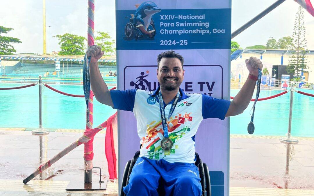 File photo of Indian para swimmer Mohammad Shams Aalam Shaikh in a wheelchair holding up medals beside a swimming pool