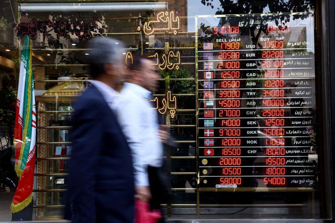 People walk past a currency exchange board in Tehran showing dollar, euro and pound rates