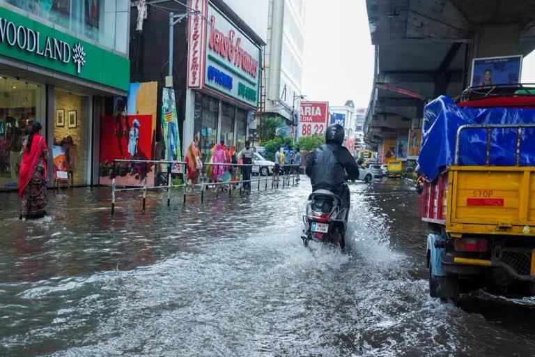 File photo of a waterlogged street in Thiruvananthapuram during heavy rain, with a motorcyclist riding through floodwater