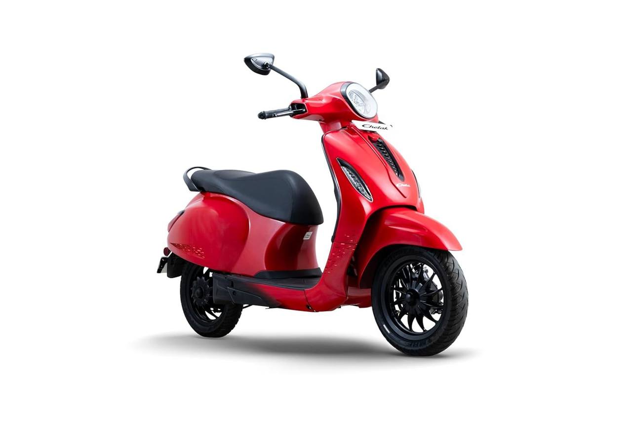 A red Bajaj Chetak electric scooter in a studio photo