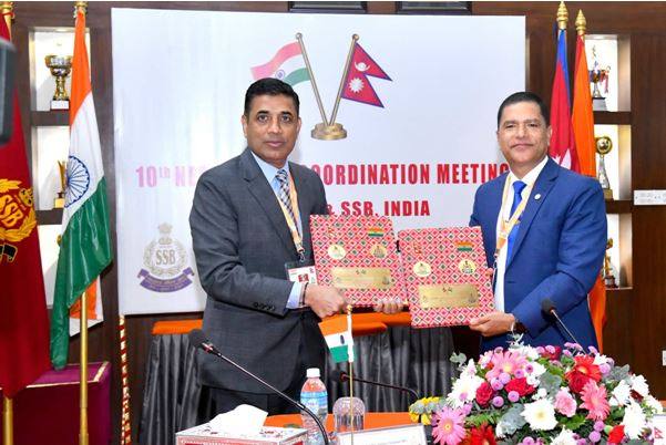 Nepal Armed Police Force and India SSB chiefs exchange meeting documents at the 10th Nepal-India Coordination Meeting in Kathmandu, with Indian and Nepali flags behind them