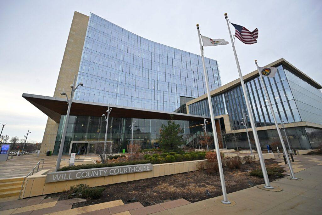 Will County Courthouse in Joliet, Illinois, a modern glass building with U.S. and Illinois flags flying in front