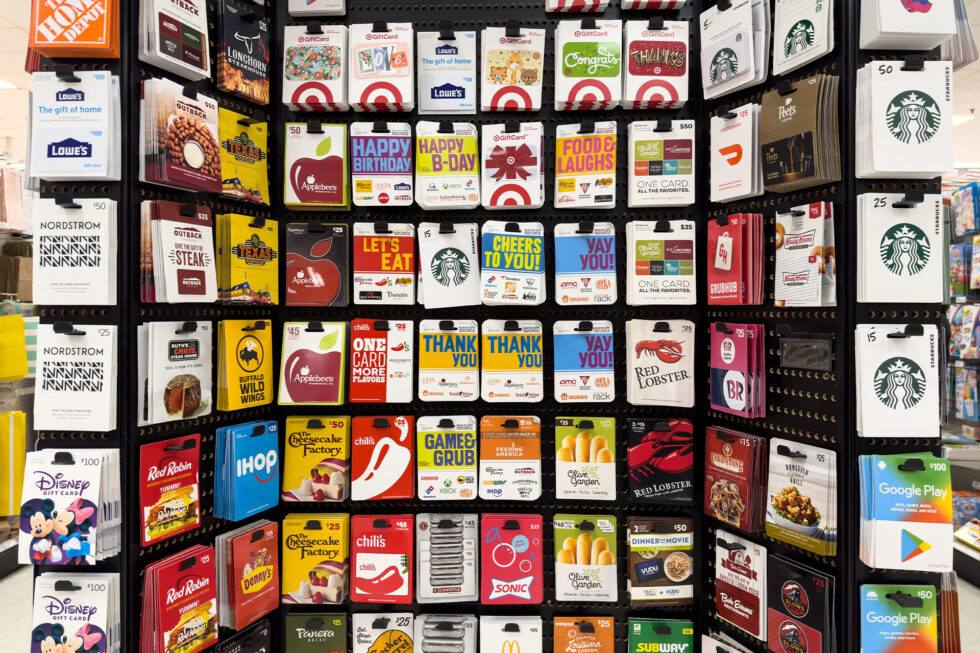 A retail gift-card display rack in a store, rows of colourful gift cards hanging for sale