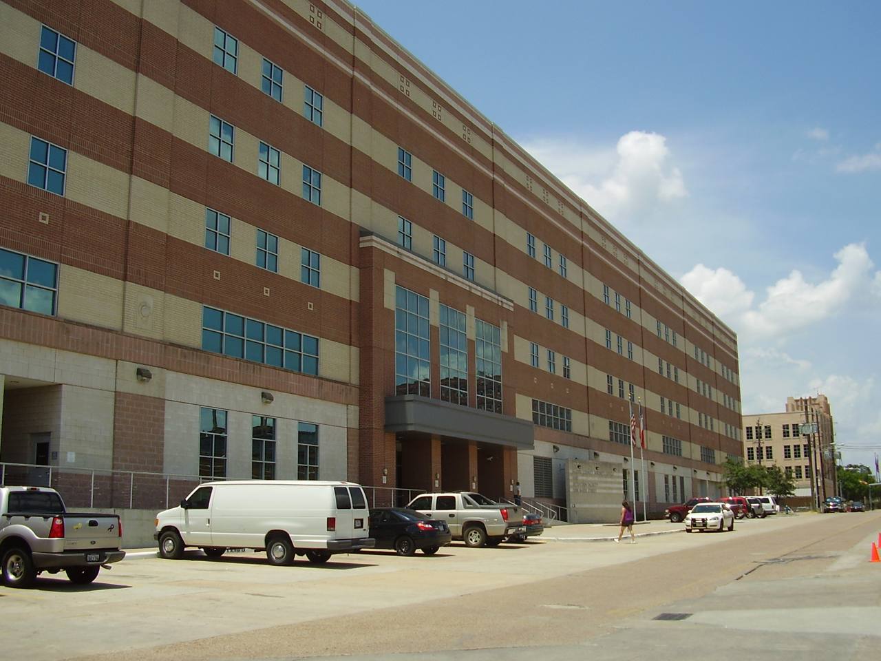 The Harris County Jail building in Houston, Texas — a striped brick institutional building photographed from the street under a blue sky
